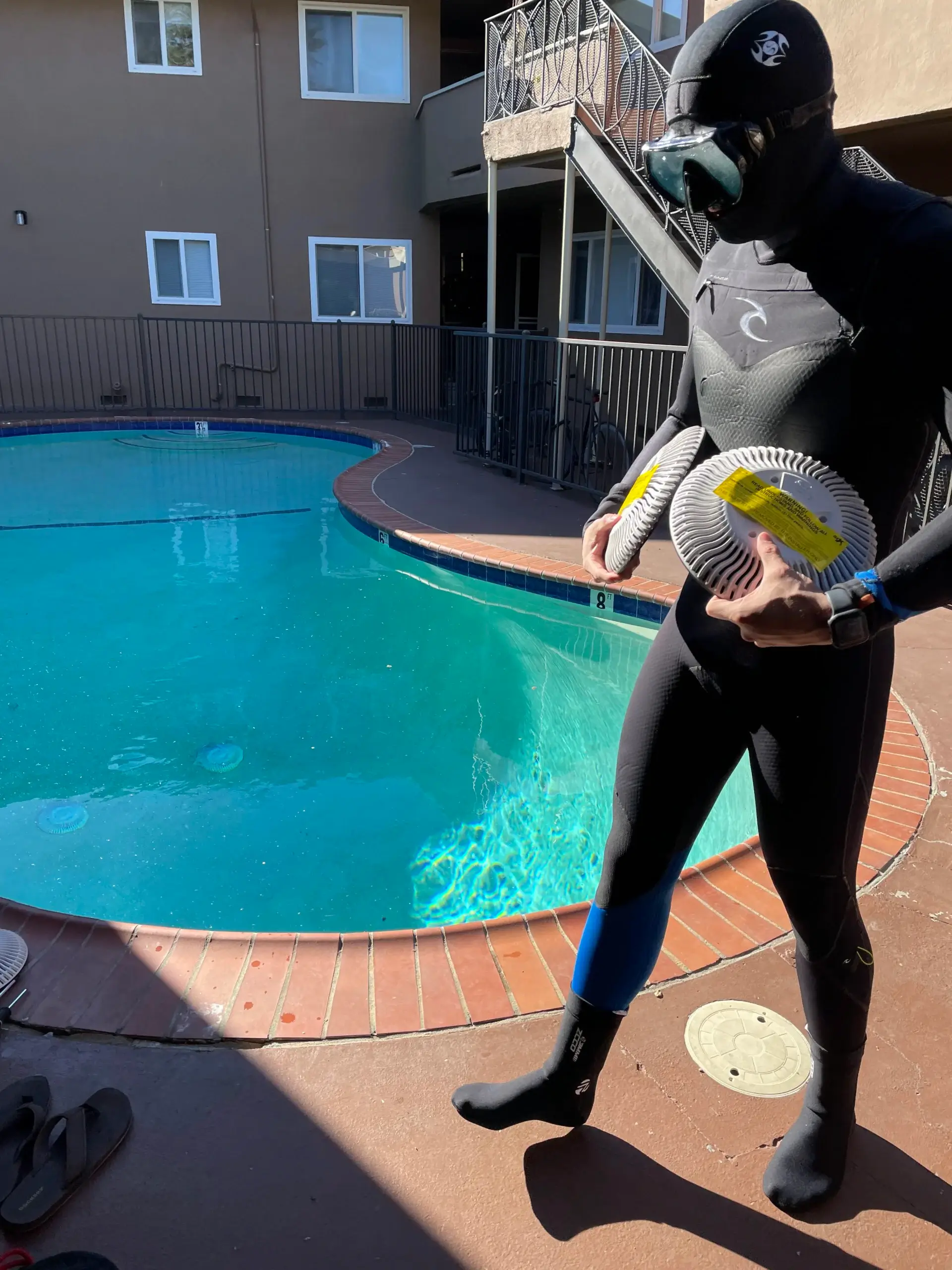 A man in a wetsuit standing next to a pool.