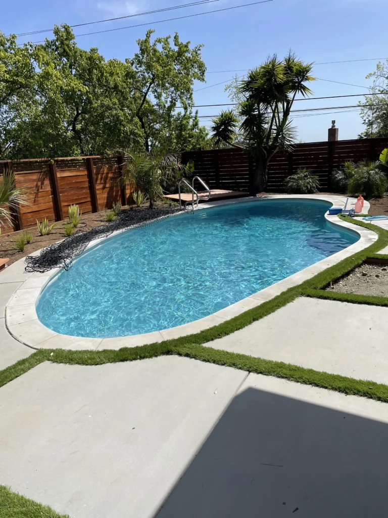 A swimming pool in a backyard with artificial grass.